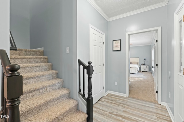 staircase featuring crown molding, wood-type flooring, and a textured ceiling