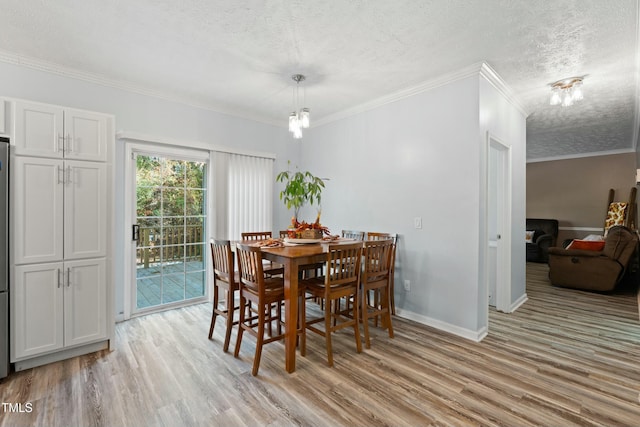 dining room featuring crown molding, light hardwood / wood-style flooring, and a textured ceiling