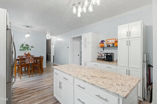 kitchen featuring a center island, hanging light fixtures, light hardwood / wood-style floors, a textured ceiling, and white cabinets