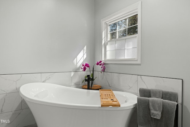 bathroom with a tub and tile walls