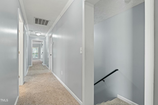 hall with light carpet, a textured ceiling, and ornamental molding