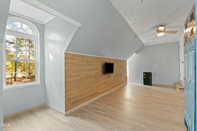 additional living space with a textured ceiling, light wood-type flooring, vaulted ceiling, and ceiling fan