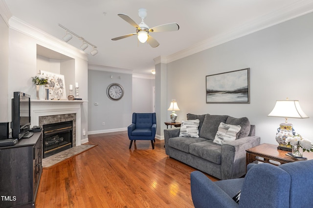 living room with ceiling fan, wood-type flooring, track lighting, a fireplace, and ornamental molding