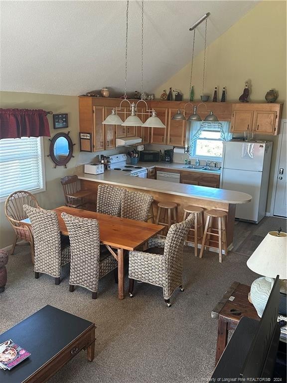 kitchen with white appliances, sink, hanging light fixtures, vaulted ceiling, and kitchen peninsula