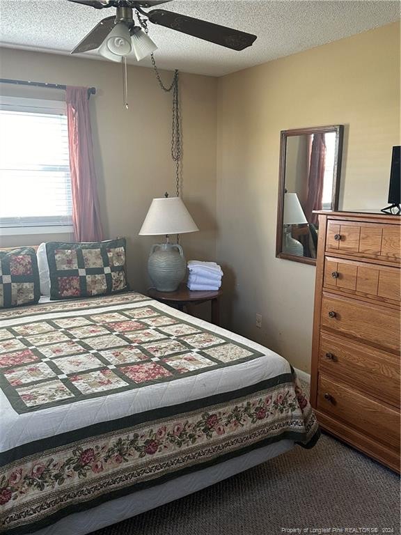 carpeted bedroom with a textured ceiling and ceiling fan