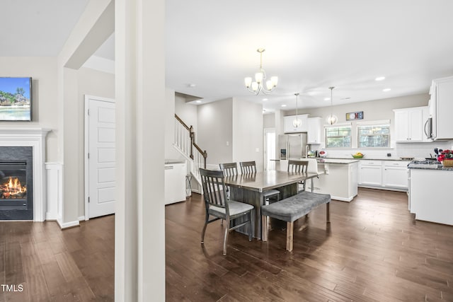 dining area with a fireplace, dark wood-type flooring, and a notable chandelier