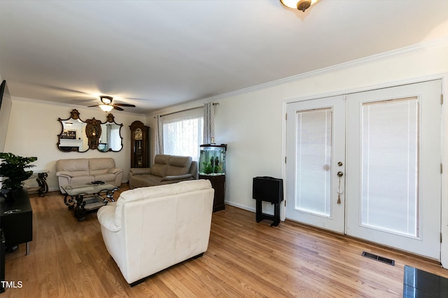 living room featuring crown molding, light hardwood / wood-style flooring, ceiling fan, and french doors