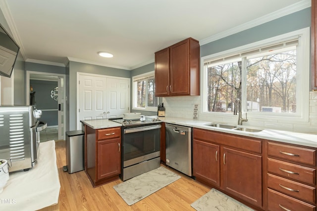 kitchen with sink, tasteful backsplash, crown molding, appliances with stainless steel finishes, and light wood-type flooring