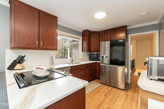 kitchen featuring sink, light hardwood / wood-style floors, decorative backsplash, black appliances, and ornamental molding