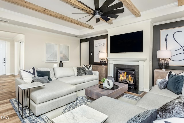 living room featuring beam ceiling, hardwood / wood-style flooring, ceiling fan, and ornamental molding