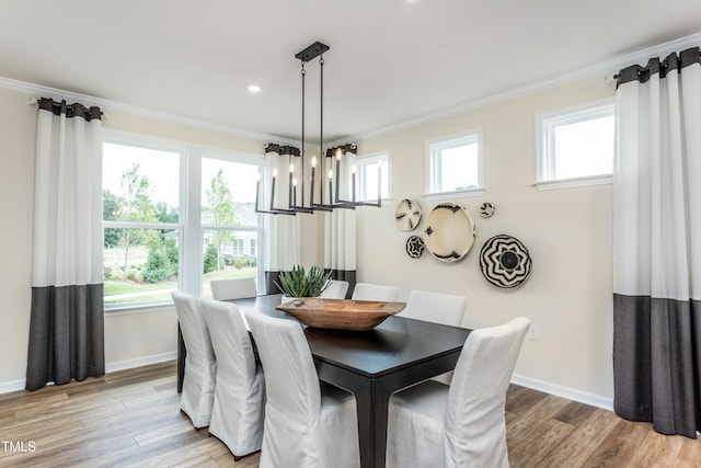 dining space with light hardwood / wood-style flooring, an inviting chandelier, a healthy amount of sunlight, and ornamental molding