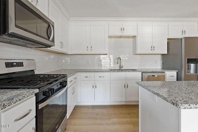 kitchen featuring decorative backsplash, light wood-type flooring, stainless steel appliances, sink, and white cabinetry