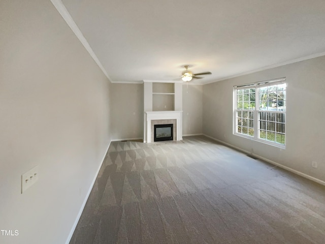 unfurnished living room with ceiling fan, carpet floors, crown molding, and a tile fireplace