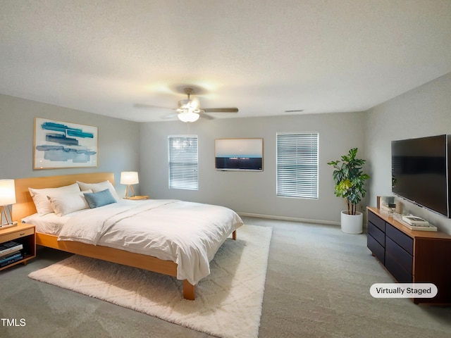 carpeted bedroom featuring ceiling fan and a textured ceiling