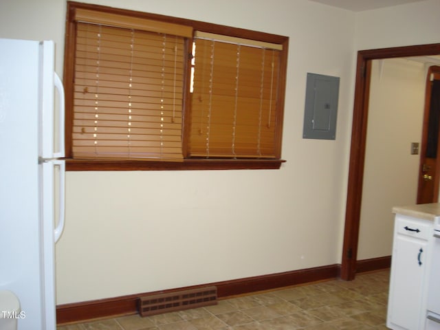 interior space with white refrigerator, white cabinetry, and electric panel