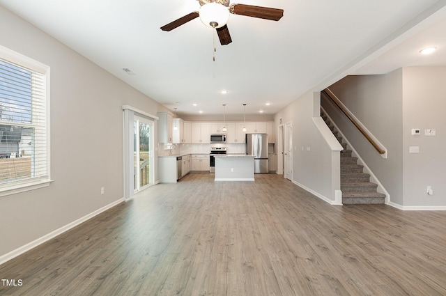 unfurnished living room featuring ceiling fan and light hardwood / wood-style flooring