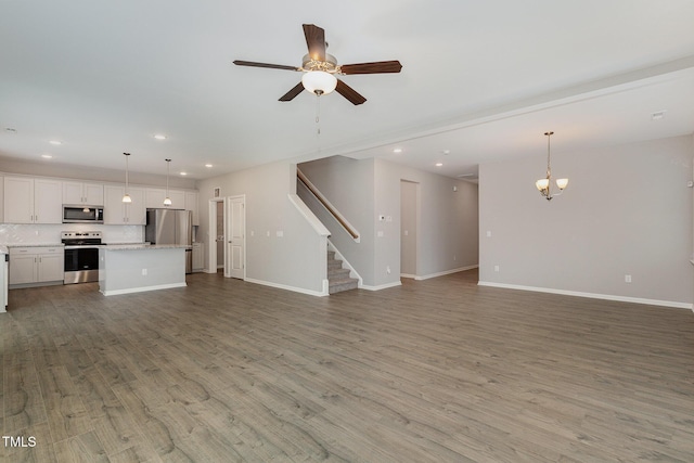 unfurnished living room featuring hardwood / wood-style flooring and ceiling fan with notable chandelier