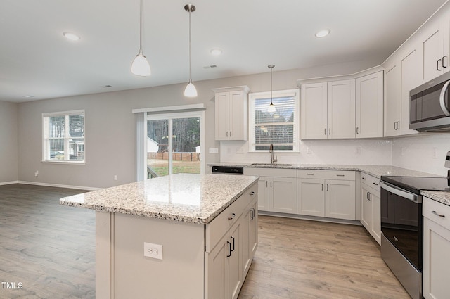 kitchen featuring sink, a center island, pendant lighting, white cabinets, and appliances with stainless steel finishes