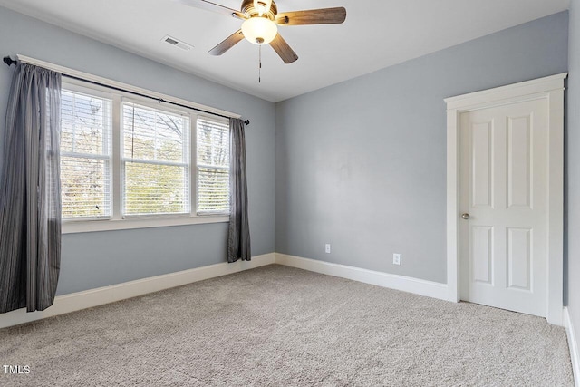 empty room featuring baseboards, a ceiling fan, visible vents, and light colored carpet