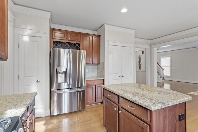 kitchen with light stone counters, stainless steel fridge, a kitchen island, and light wood-style flooring