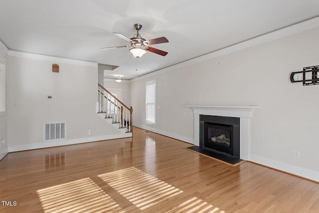 unfurnished living room featuring light wood finished floors, visible vents, a fireplace with flush hearth, stairs, and crown molding