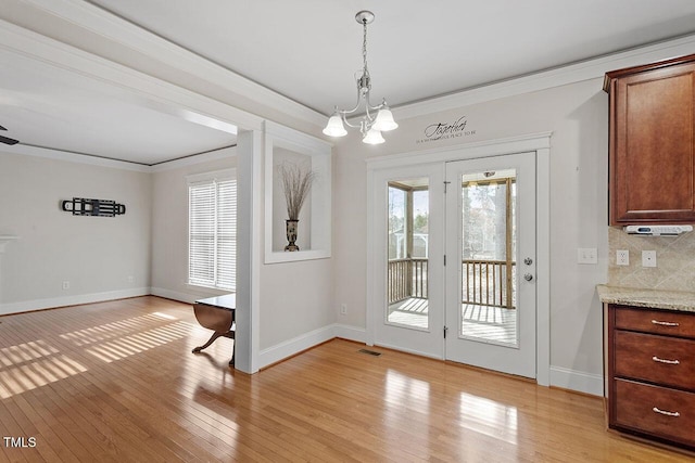 doorway to outside featuring ornamental molding, visible vents, light wood-style flooring, and baseboards