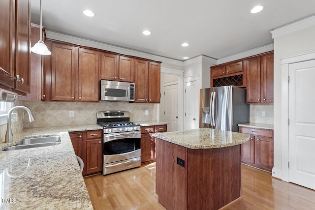 kitchen with stainless steel appliances, light stone counters, a sink, and pendant lighting