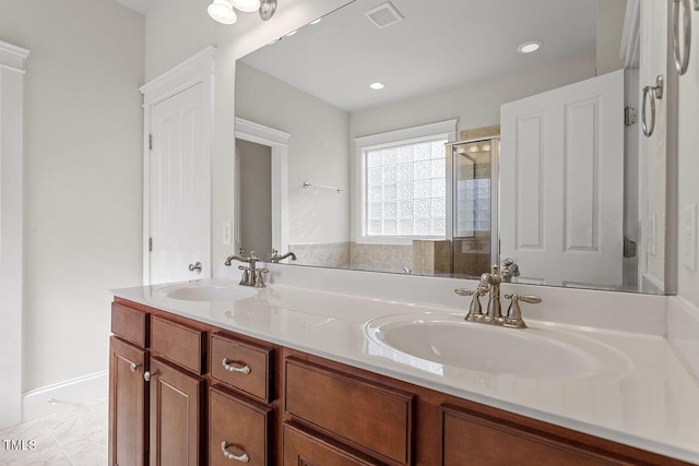 full bath featuring double vanity, a shower stall, visible vents, and a sink