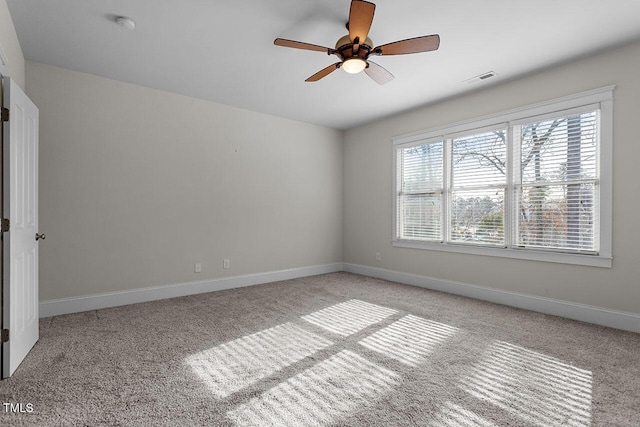 empty room with a ceiling fan, visible vents, light carpet, and baseboards