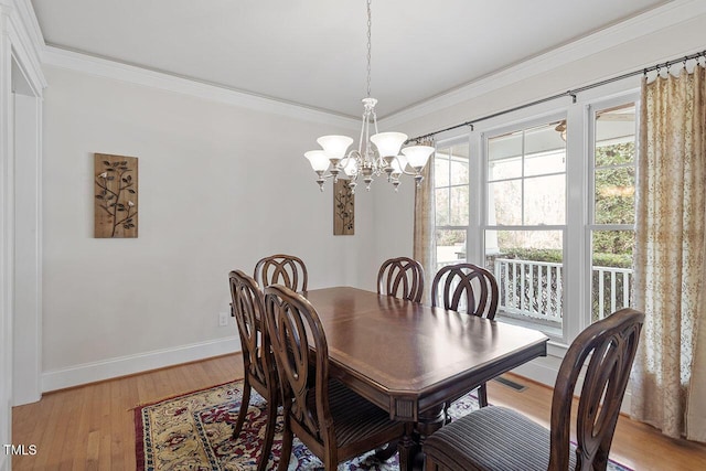 dining space with light wood-type flooring, baseboards, a chandelier, and crown molding