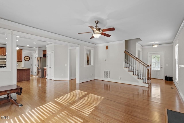 living area with baseboards, visible vents, stairway, crown molding, and light wood-type flooring