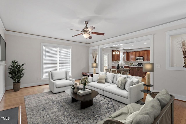 living area with baseboards, ceiling fan, light wood-type flooring, and crown molding