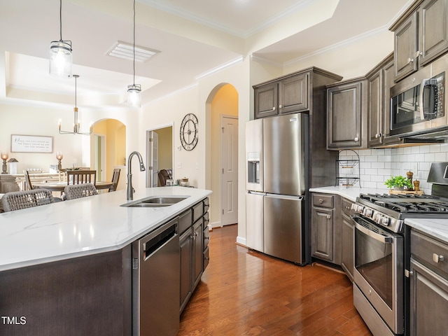 kitchen featuring dark brown cabinetry, stainless steel appliances, a kitchen island with sink, dark wood-type flooring, and sink