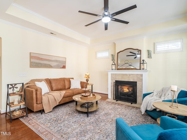 living room with hardwood / wood-style floors, ceiling fan, ornamental molding, and a tiled fireplace