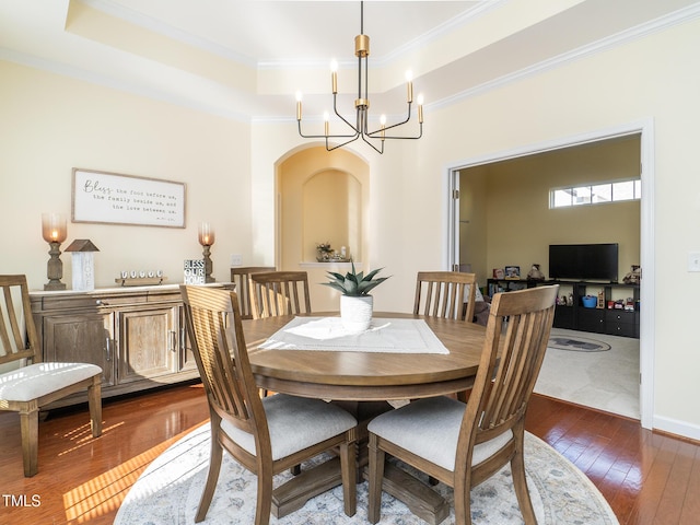 dining space with dark hardwood / wood-style flooring, crown molding, and an inviting chandelier