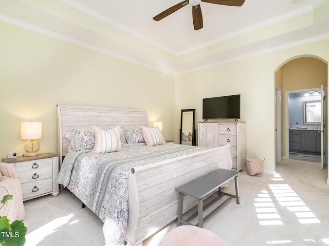 carpeted bedroom with connected bathroom, a raised ceiling, ceiling fan, and crown molding