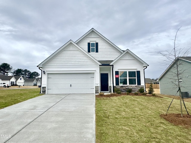 view of front of home featuring a front lawn, an attached garage, stone siding, and driveway