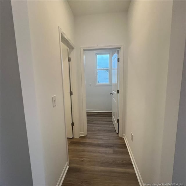 hall with dark wood-style floors and baseboards