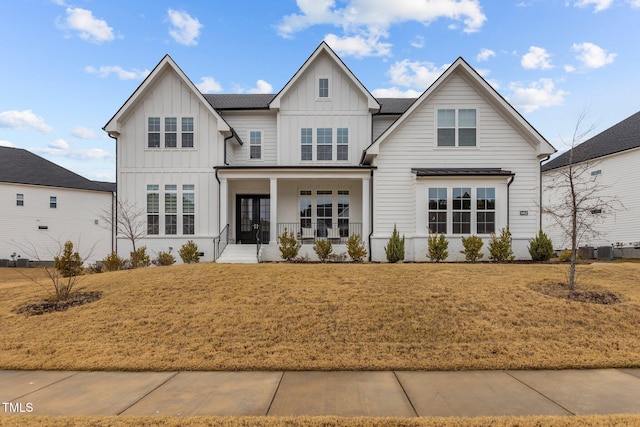 view of front of house with central AC, covered porch, and a front lawn