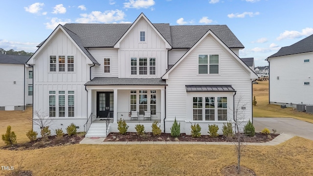 view of front of home featuring central AC unit, covered porch, and a front yard