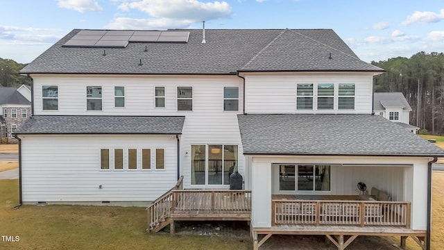 rear view of house featuring solar panels and a wooden deck