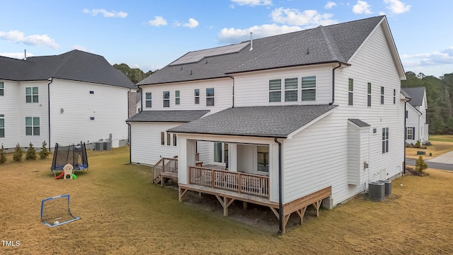 back of house featuring a lawn, central AC, a deck, and a trampoline