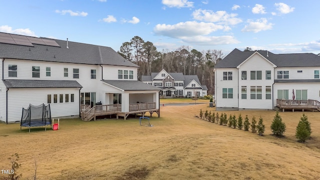 back of property with a trampoline and a wooden deck