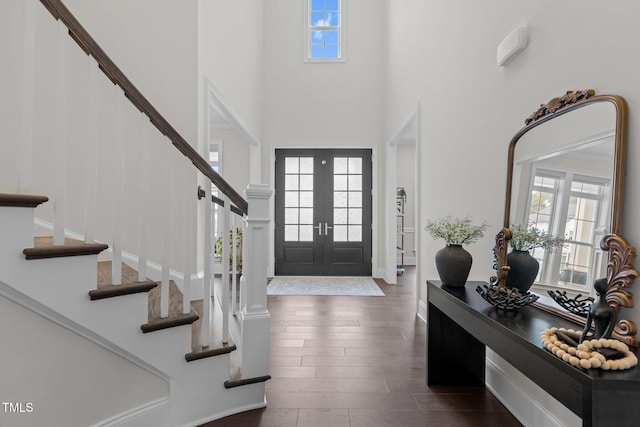 entrance foyer featuring a high ceiling, dark wood-type flooring, a wealth of natural light, and french doors