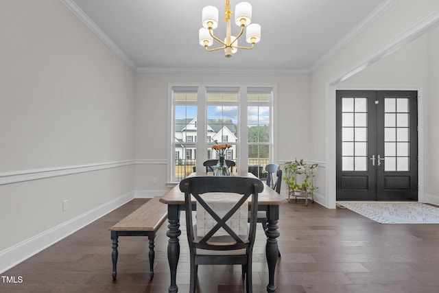 dining space featuring french doors, ornamental molding, dark wood-type flooring, and a notable chandelier