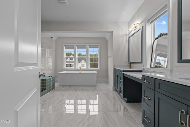 bathroom featuring a bathing tub, vanity, and a healthy amount of sunlight