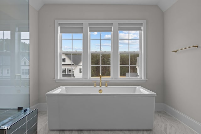 bathroom featuring tiled bath and vaulted ceiling