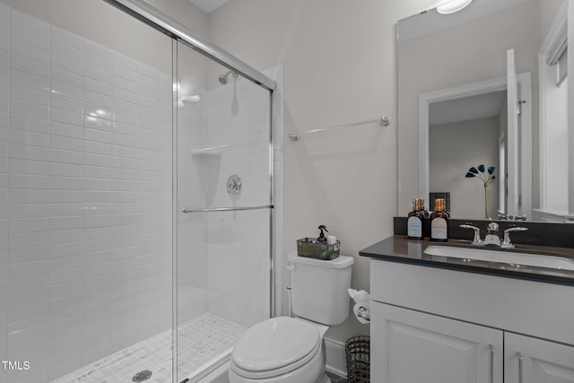 bathroom featuring vanity, a shower with shower door, and toilet