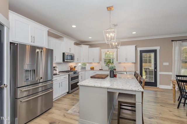 kitchen with white cabinetry, light stone counters, a center island, pendant lighting, and stainless steel appliances