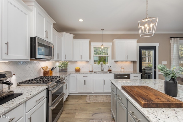 kitchen with stainless steel appliances, white cabinetry, light stone countertops, and sink